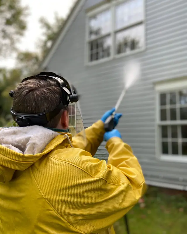 Lone Oak technician soft-washing the siding of a house
